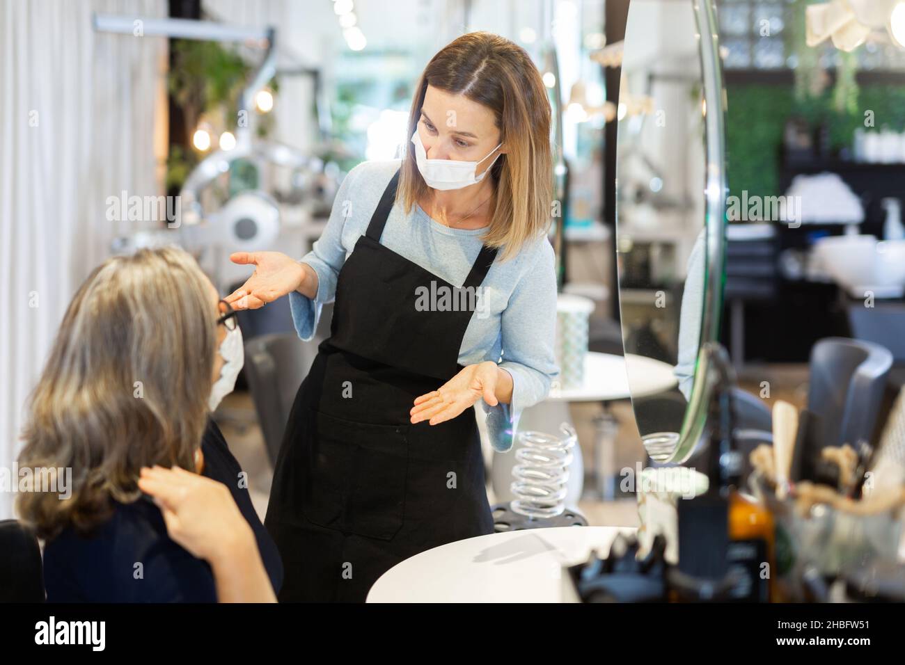 Female hairdresser in protective mask offering hairstyling to woman client Stock Photo Alamy