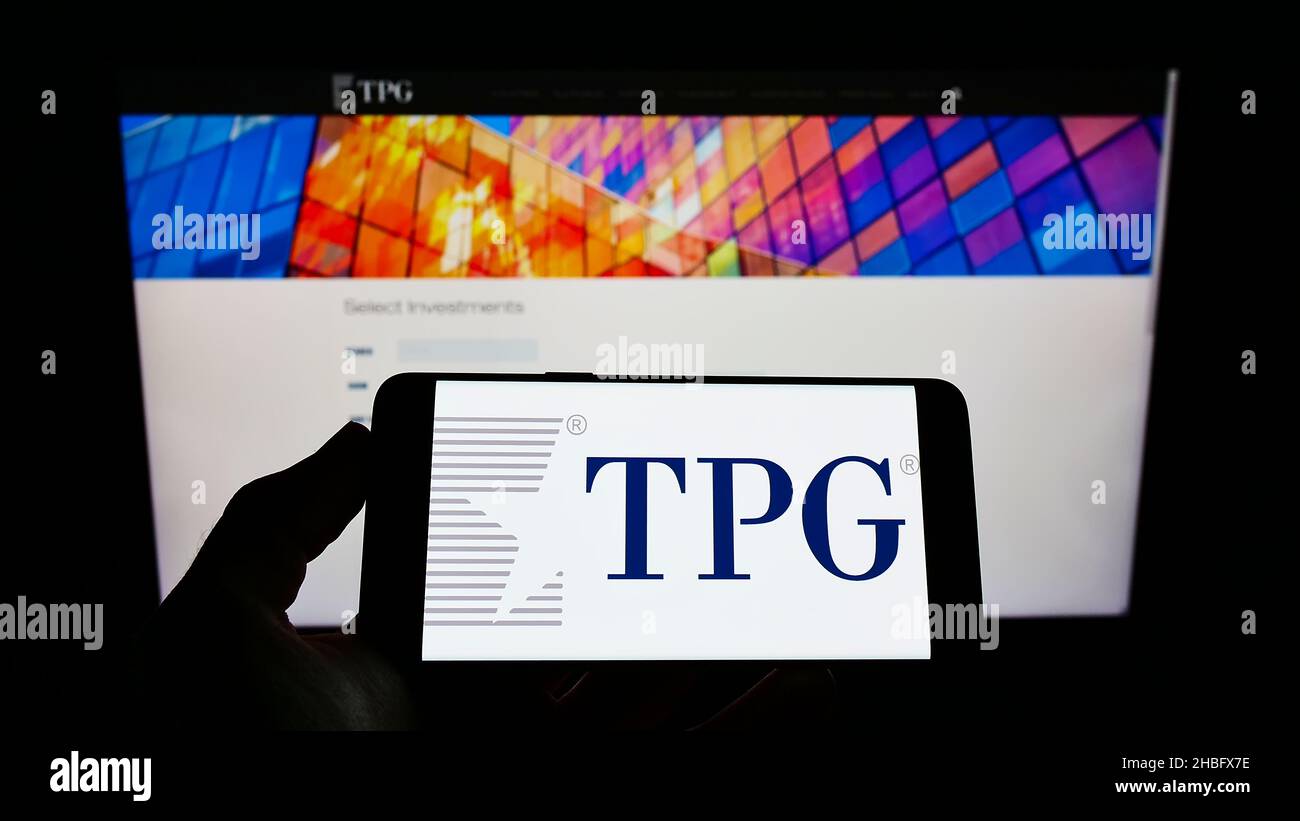 Person holding cellphone with logo of US investment company TPG Capital on screen in front of business webpage. Focus on phone display. Stock Photo