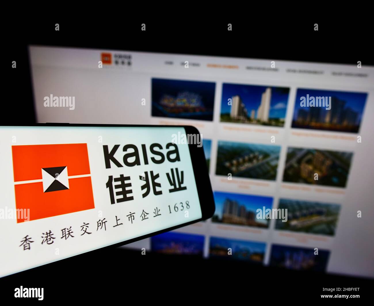Mobile phone with logo of Chinese property company Kaisa Group Holdings Ltd. on screen in front of website. Focus on left of phone display. Stock Photo