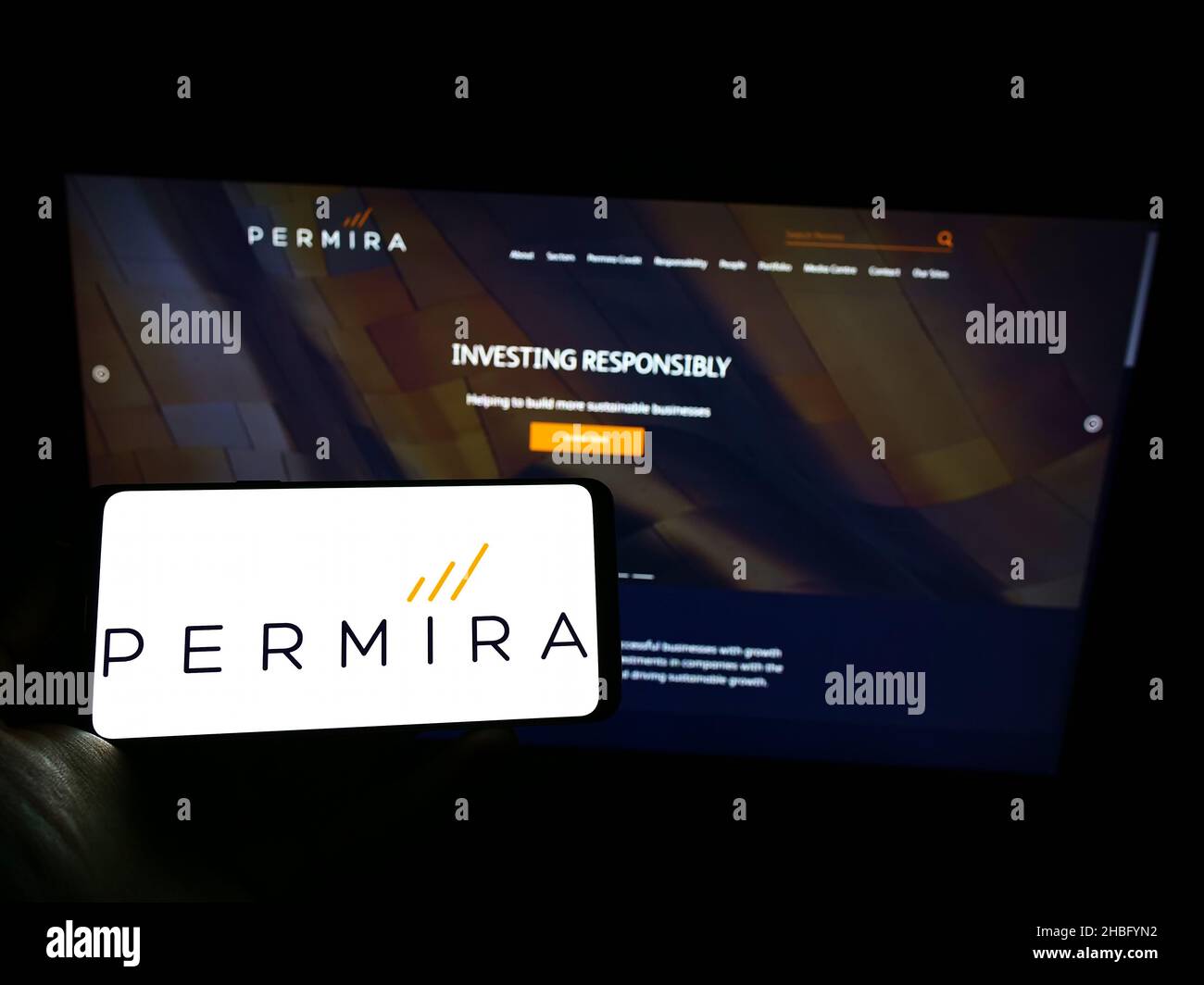 Person holding cellphone with logo of British investment company