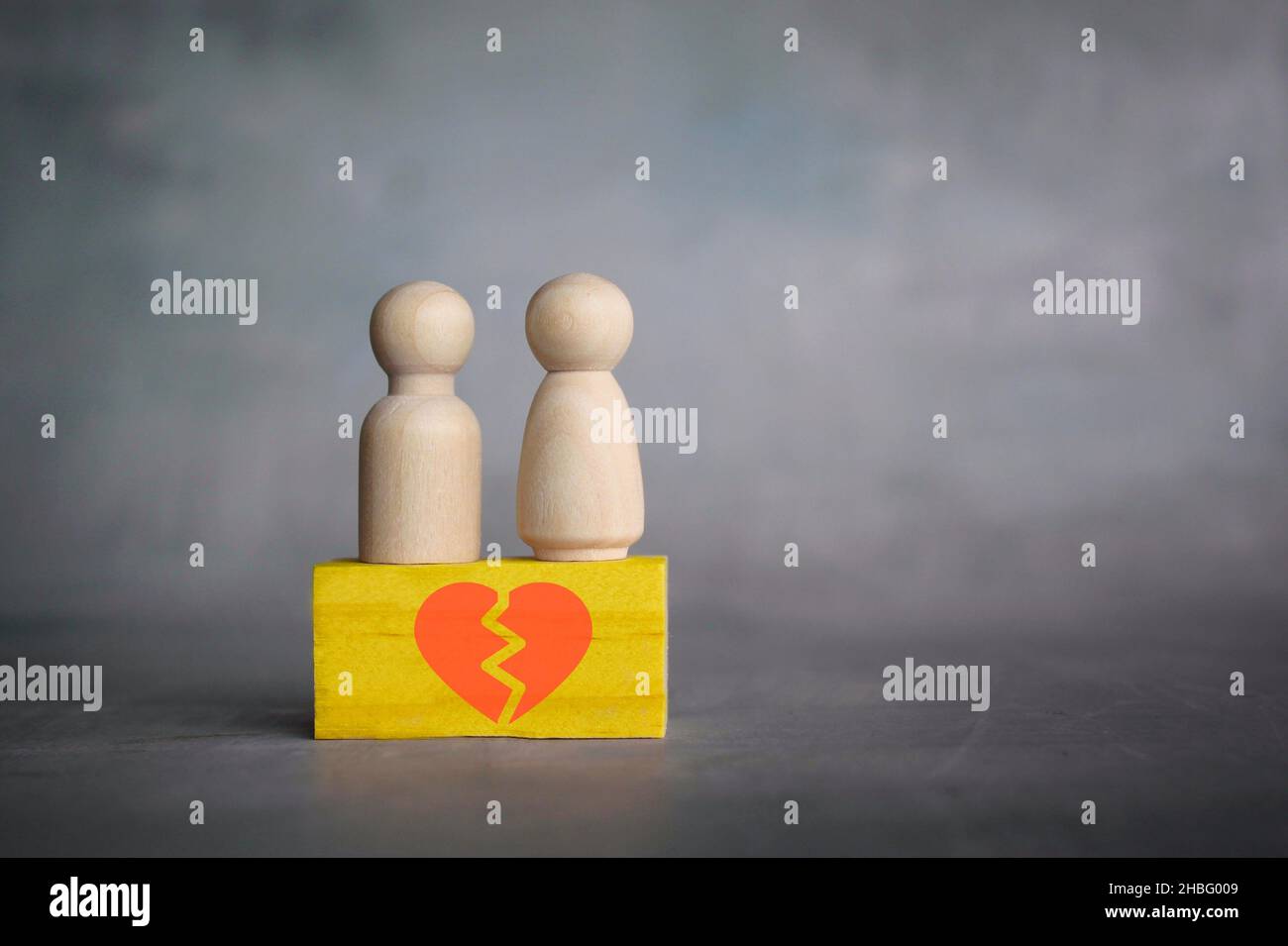 Divorce and broken relationship concept. Wooden dolls and wooden block with broken heart icon. Stock Photo