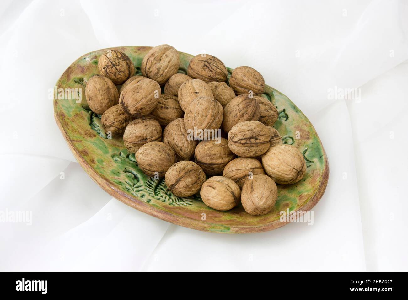 walnuts on a clay plate - white background Stock Photo