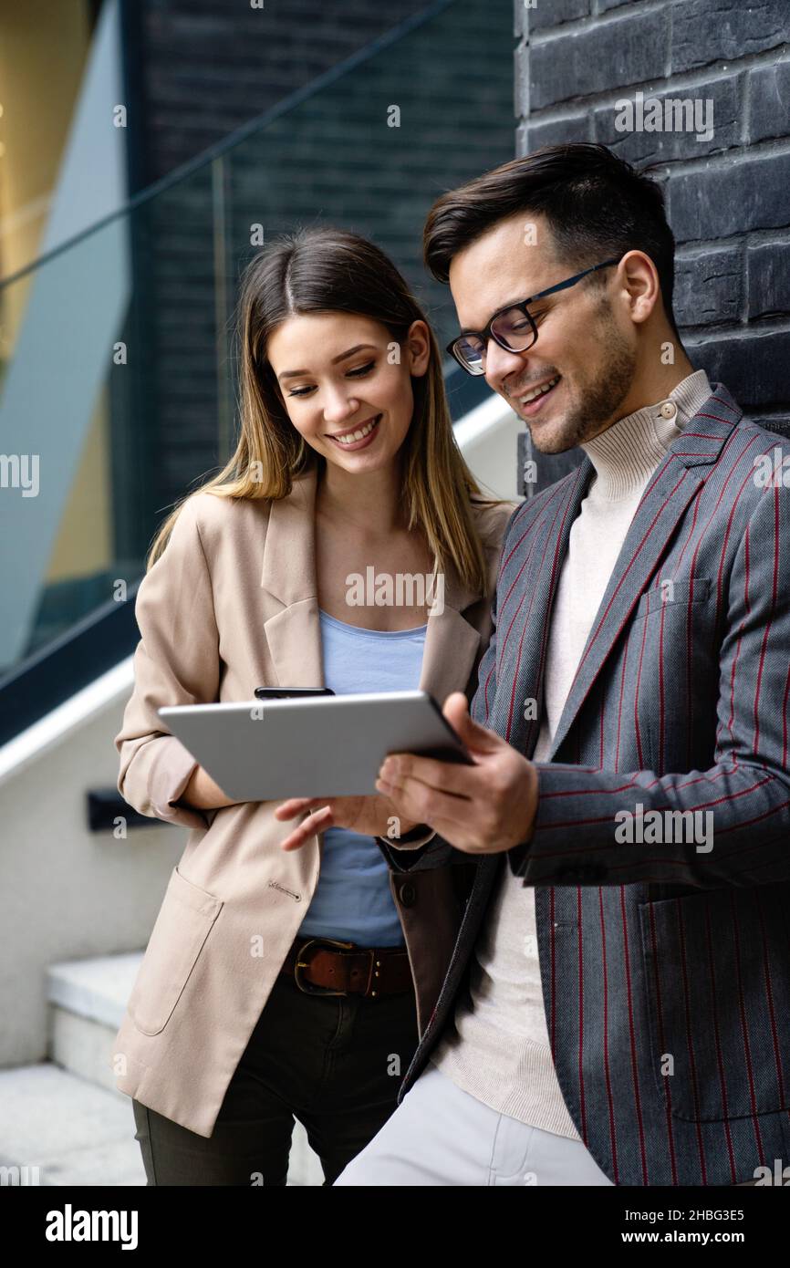 Successful young business people talking, working together in front of modern business building Stock Photo