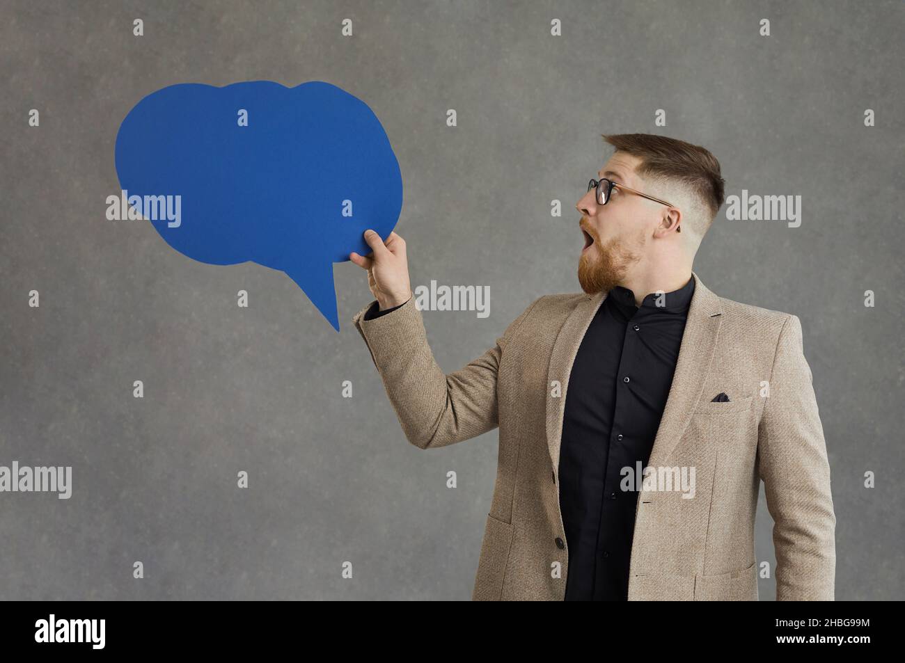 Young adult businessman looking at speech bubble with surprised emotion Stock Photo