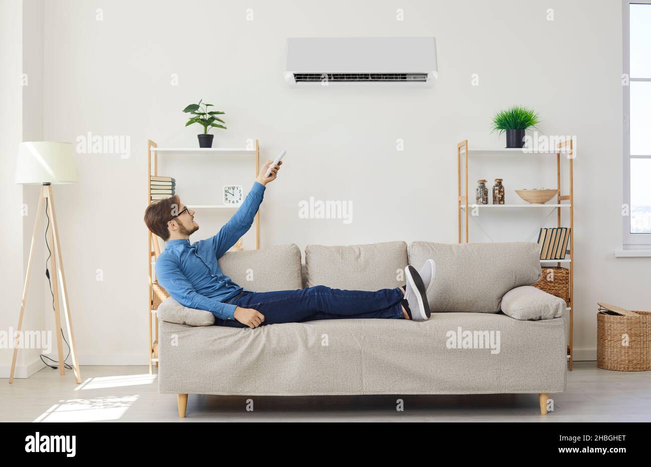 Man with remote control from air conditioner makes comfortable temperature for himself. Stock Photo