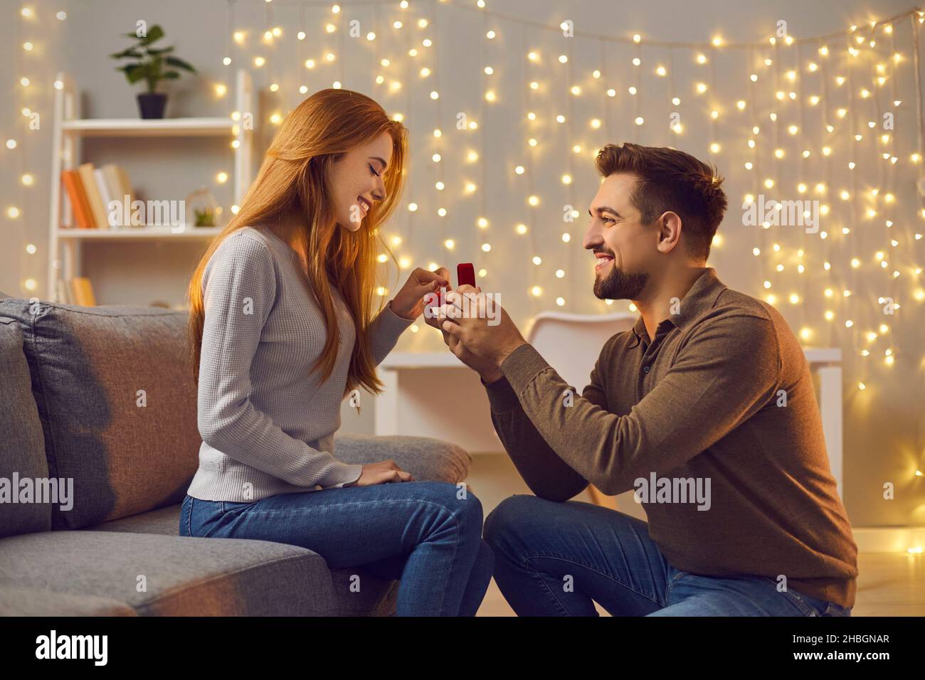 Happy young man proposing to his girlfriend and giving her a beautiful engagement ring Stock Photo
