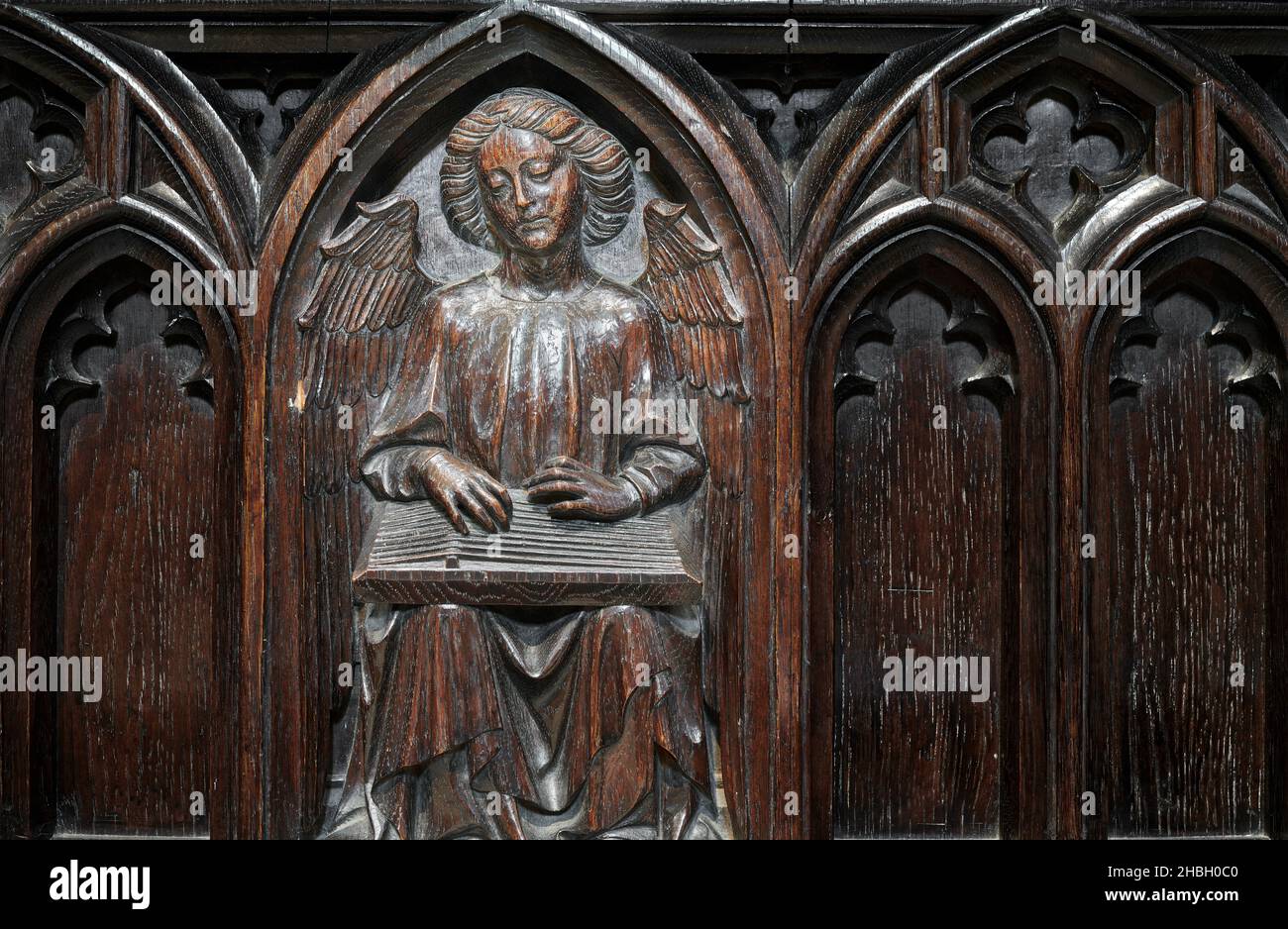 Carving of an angel with a musical instrument on the wooden bench in the choir at the cathedral of Lincoln, England. Stock Photo