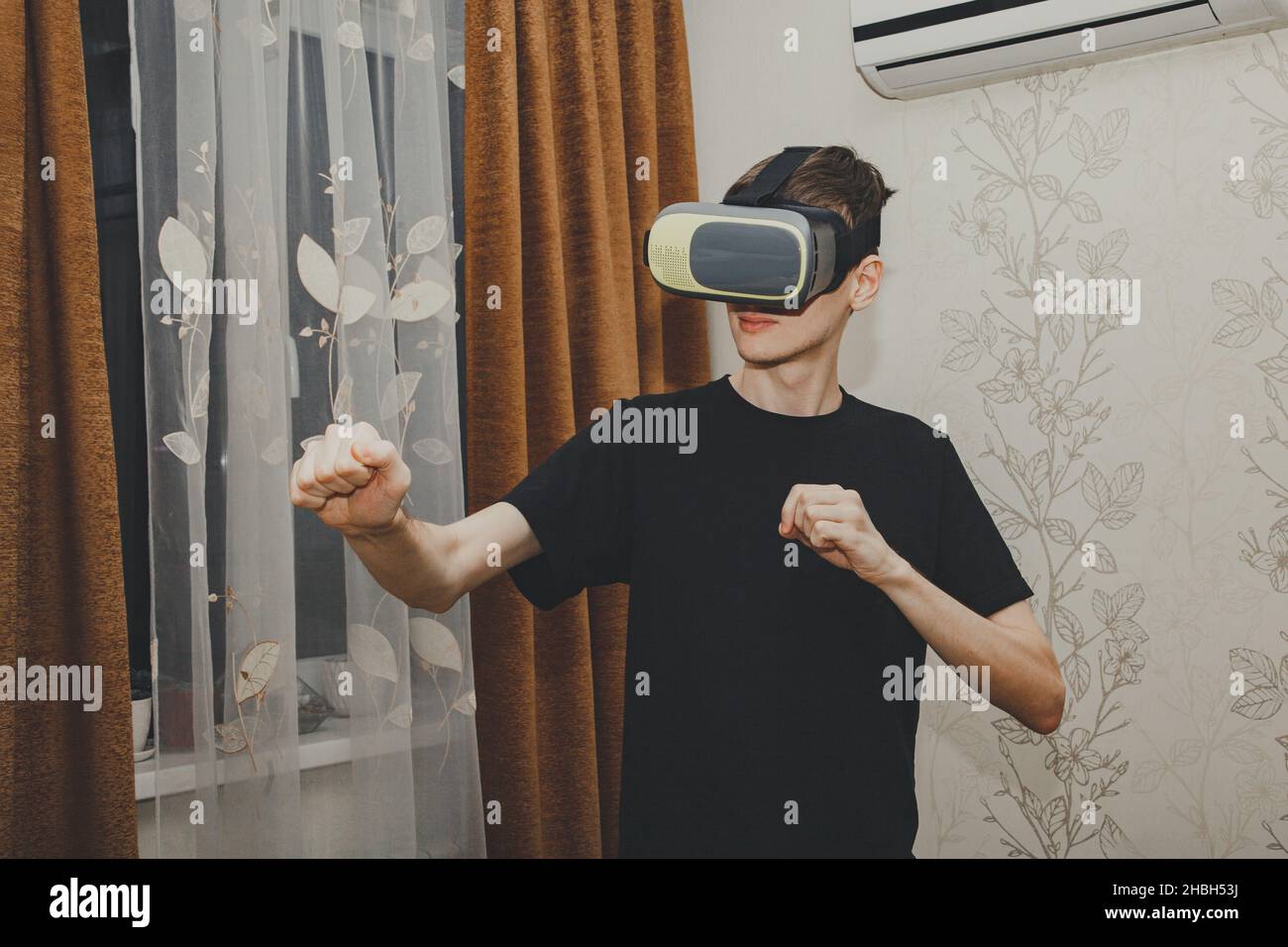 Young man in a VR helmet interacts with objects in virtual reality in ...