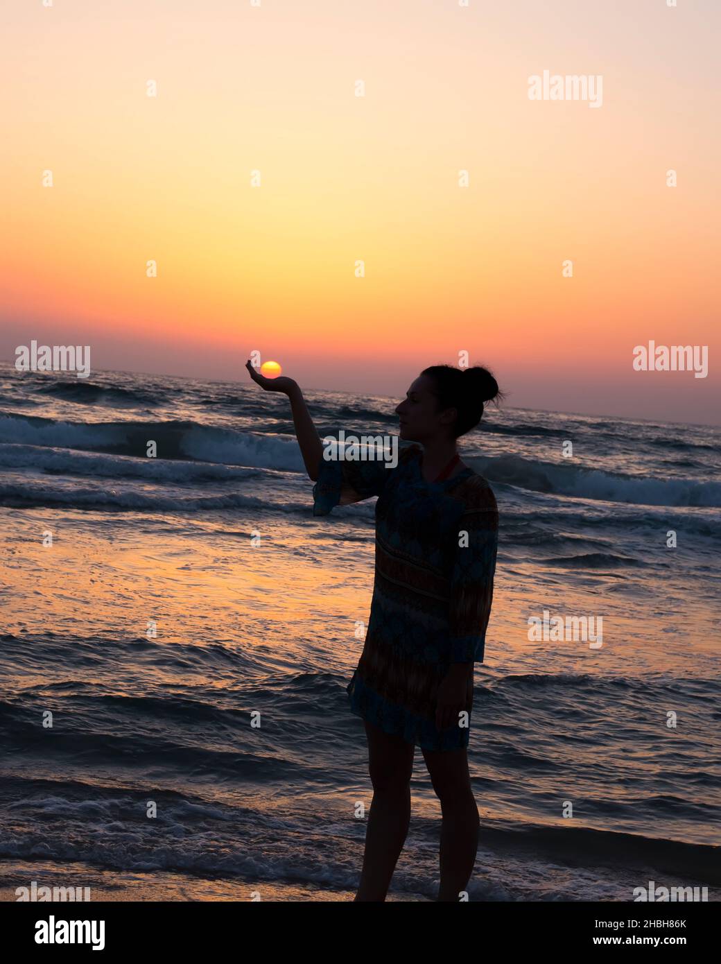 woman holds the sun as it sets in the palm of her hand Stock Photo - Alamy