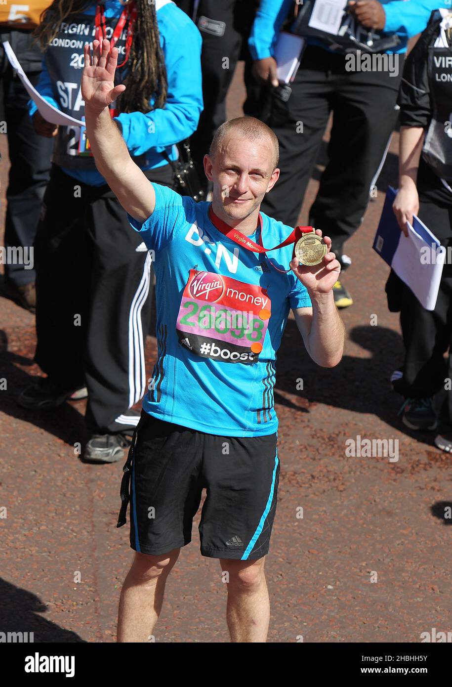 Ben Quilton with medal at the finishing line of the Virgin Money London Marathon on the Mall in London. Stock Photo