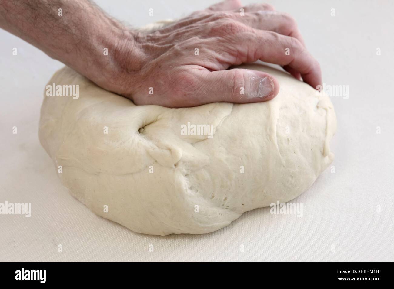 Baker kneads bread dough in a bakery Stock Photo