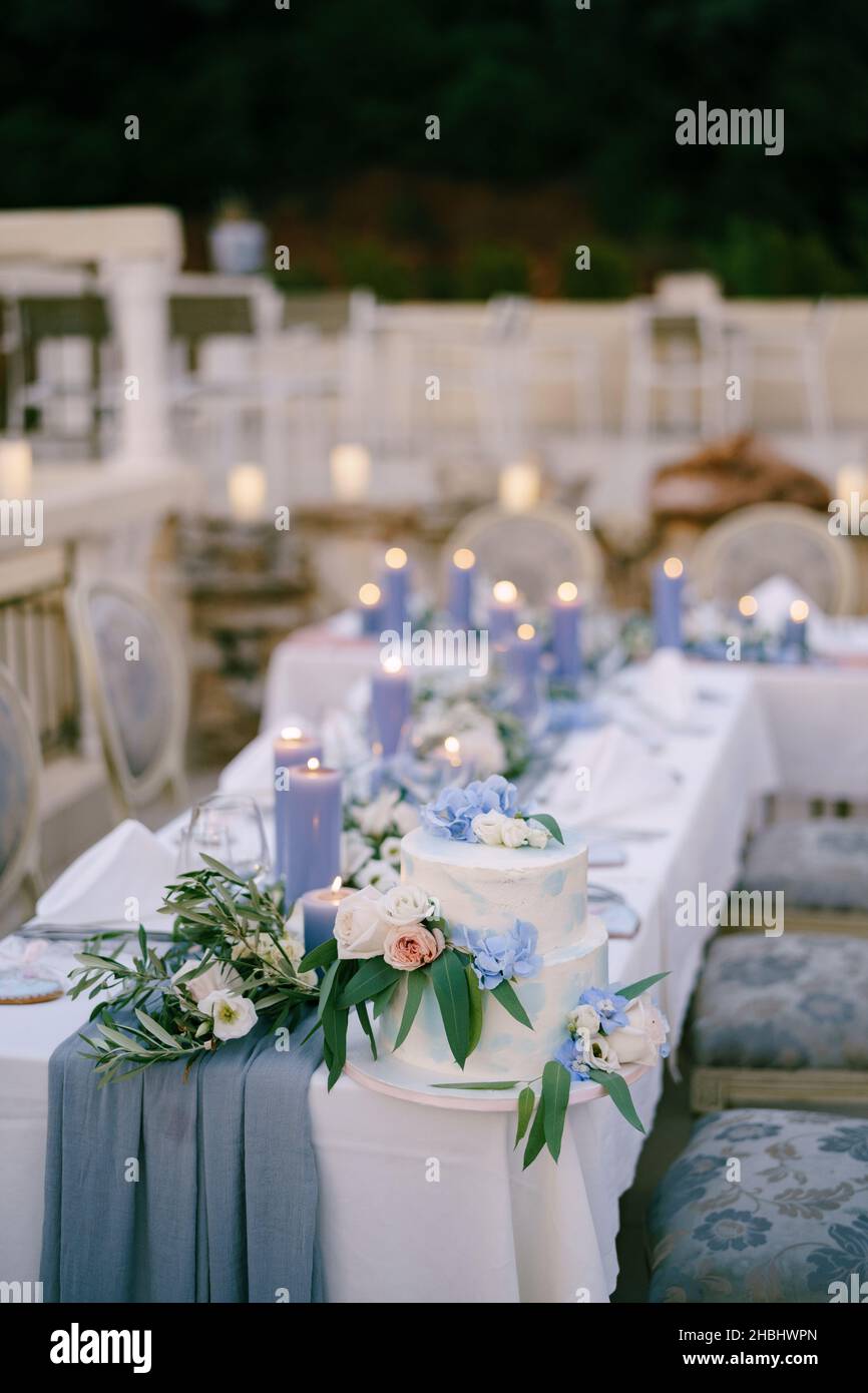 White bunk wedding cake stands on a set table with candles Stock Photo
