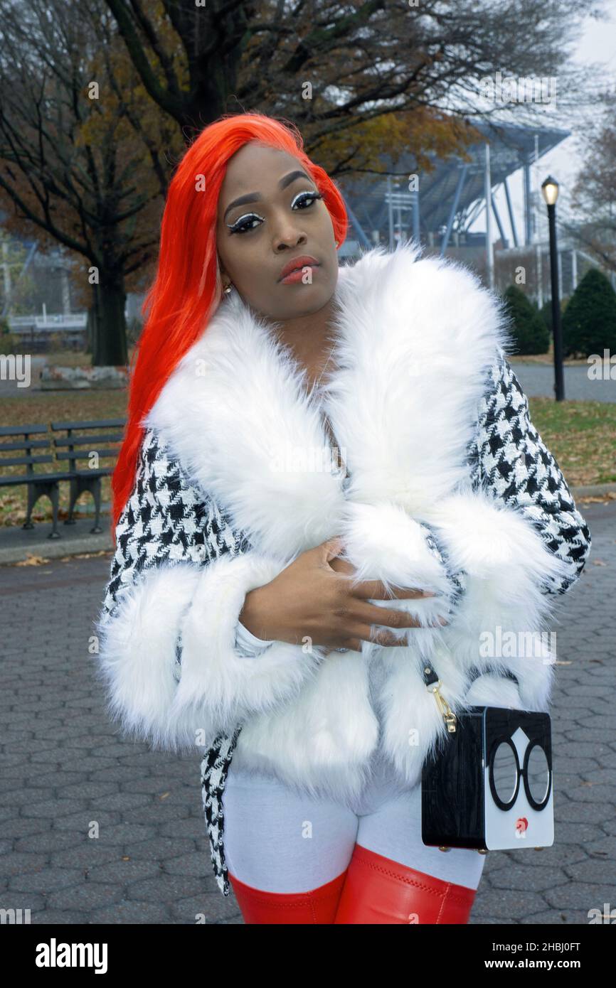 Posed portrait of a pretty lady with orange hair and long fingernails. In a park in Queens, New York City. Stock Photo