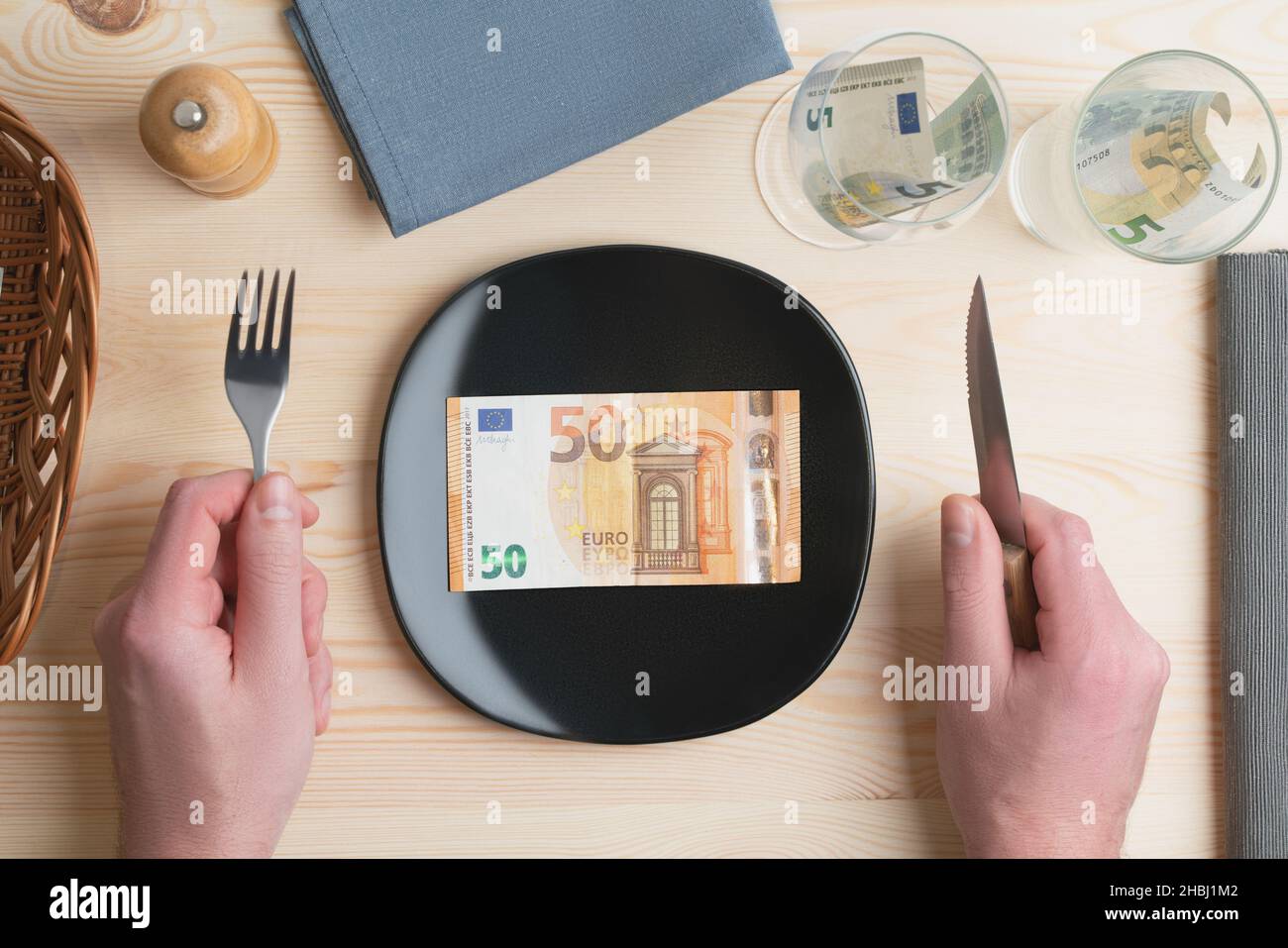 Conceptual studio shot of dinner table with euro bank notes on the plate instead of food. Concept for rising food prices, inflation, economic crisis Stock Photo