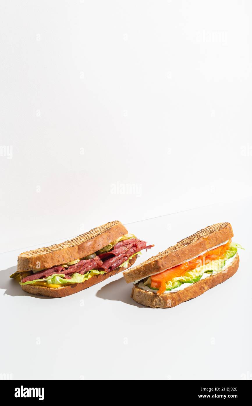 Two sandwiches with salmon, ham, cheese and salad on grey dark shadow Stock Photo