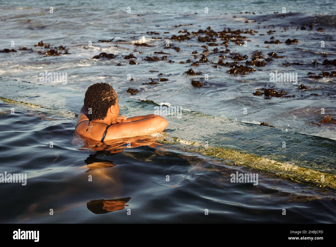 Contemplating South Africa's False Bay coastline from the St James' Dalebrook tidal pool near Cape Town Stock Photo