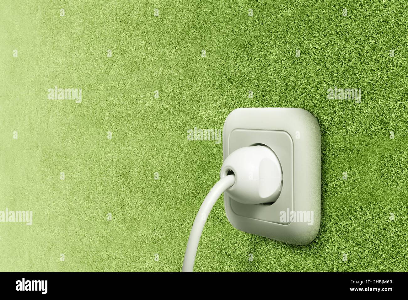Electric plug into a green wall power socket. Green Power Concept Stock