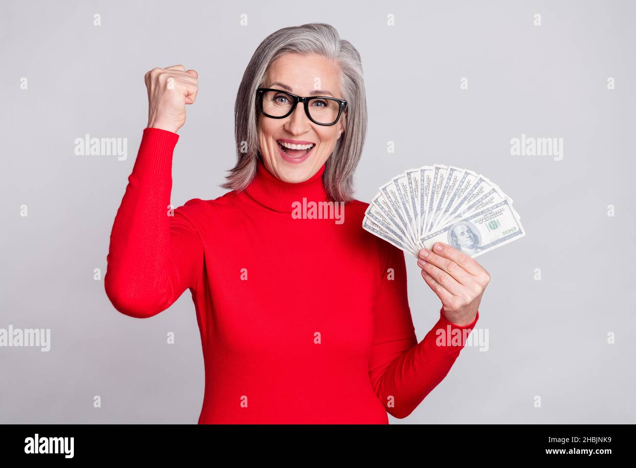Photo of charming happy amazed old woman winner hold hands money usd ...