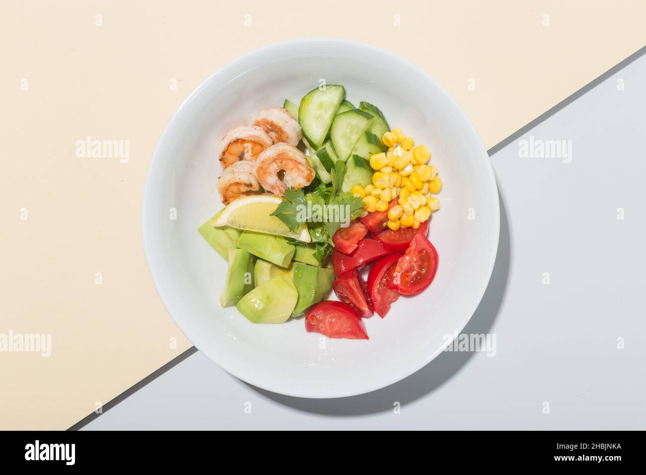 Fresh Avocado, shrimps salad with lettuce green mix, cherry tomatoes, herbs and olive oil, lemon dressing. healthy food Stock Photo