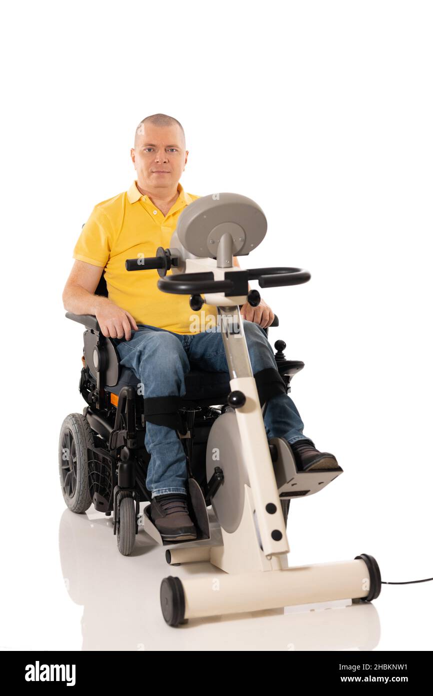 Disabled man have a rehabilitation exercises for legs. Hands free up. Motorcycle for legs and hands. Isolated on the white background Stock Photo