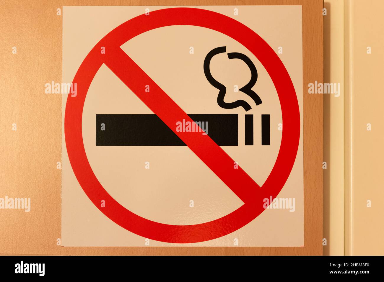 No smoking sign on the wall in the corridor of the room. A bright red circle with a crossed out smoking cigarette. Close-up Stock Photo