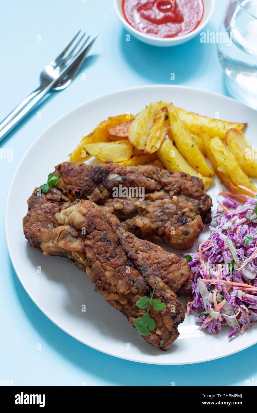 A traditional American dinner of fried ribs, fried potatoes and coleslaw. Stock Photo