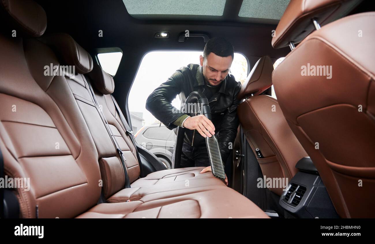 Handyman vacuuming car front textile seat with vacuum cleaner. man cleaning  work machine Stock Photo - Alamy