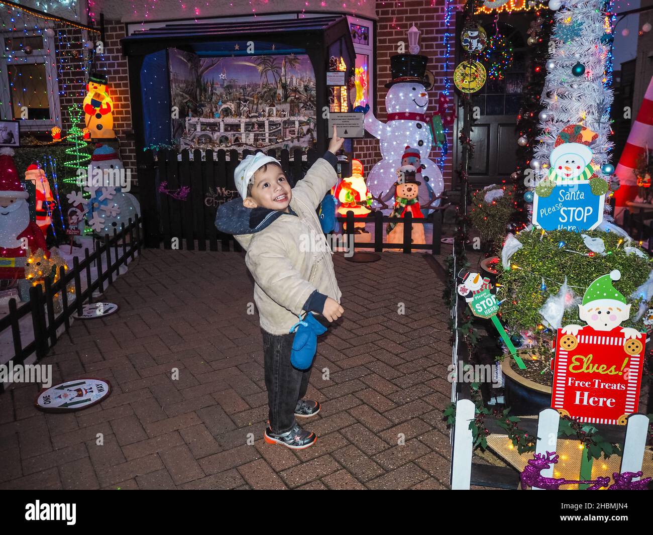 3 year old Jenson Holt Tsang enjoys the  Christmas House lights in Croxley Green - Charity Christmas House in Winton Drive, Croxley Green, Hertfordshire England, decorated by husband & wife Mr & Mrs Eleno & Margaret Pulis. Mr Eleno Pulis states that it  took 5 weeks to decorate entire house to raise money for local charity Watford Mencap and Great Ormond Street Hospital. They aim to raise over £1000 through their just giving page: https://www.justgiving.com/fundraising/margaret-pulis Stock Photo