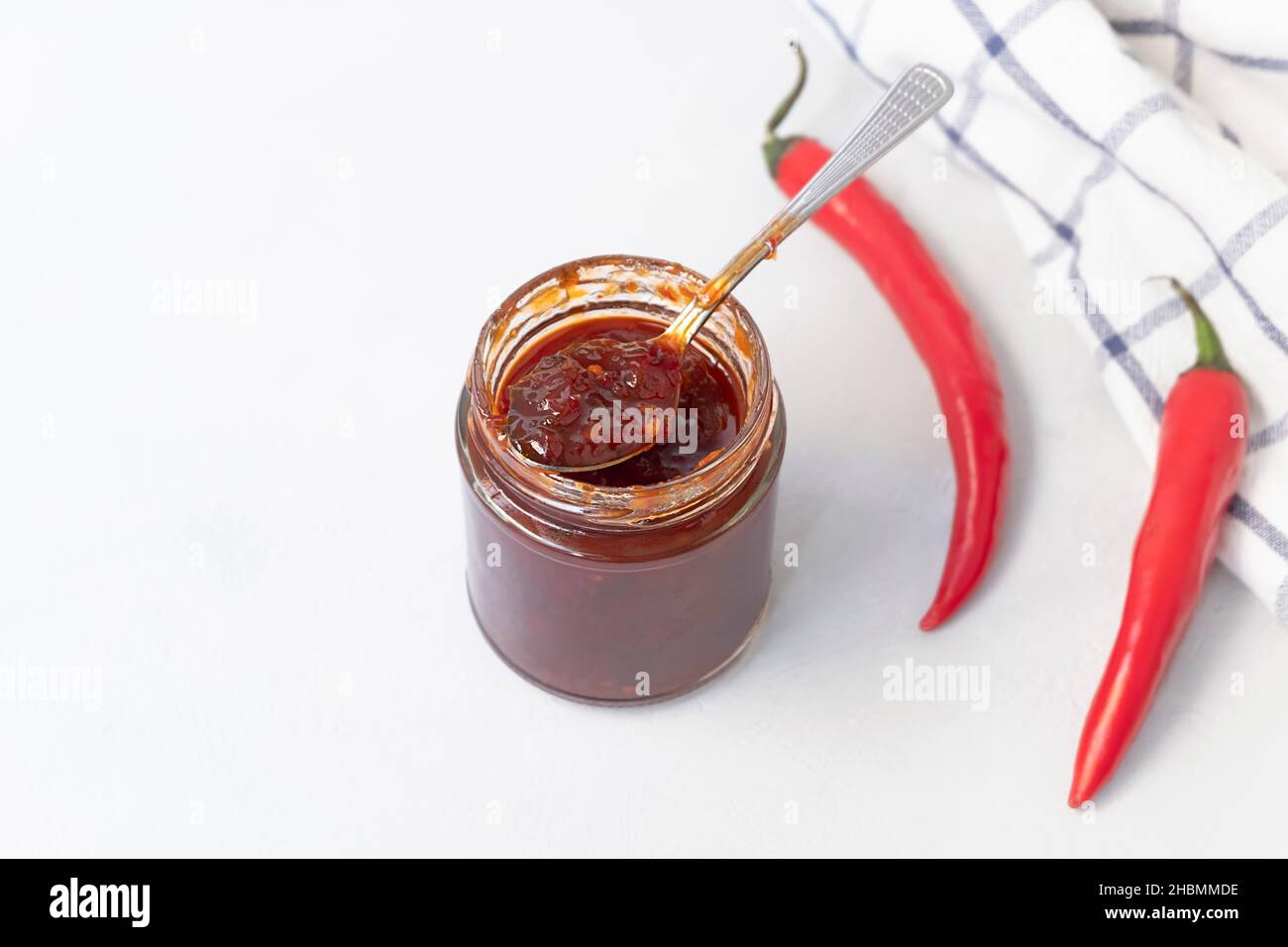 Above view of jar with sweet spicy jam made from chili pepper on neutral grey background with copy space, selective focus Stock Photo