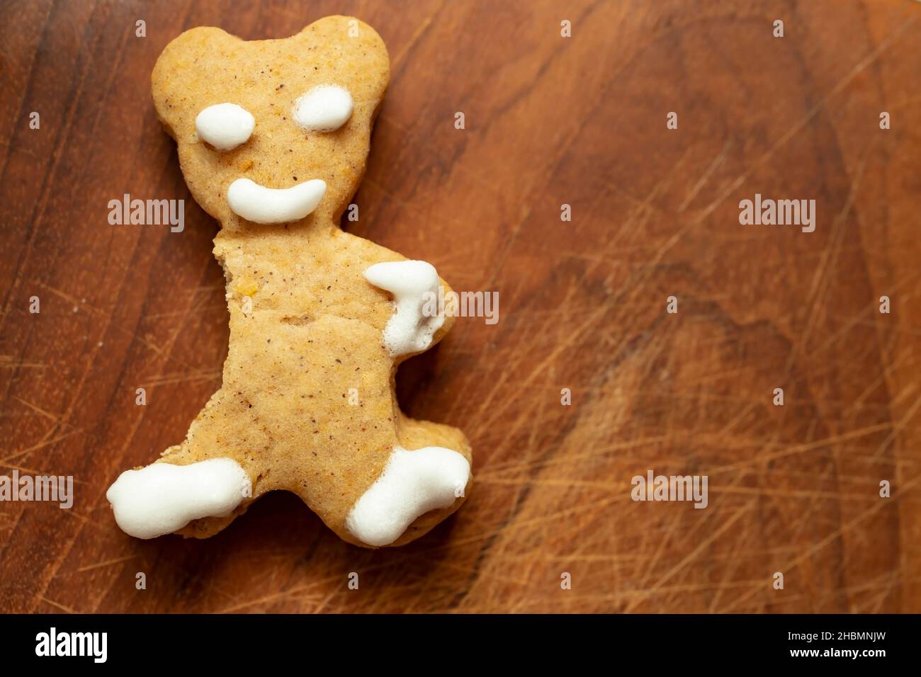 bitten gingerbread bear , on a wood chopping board texture Stock Photo