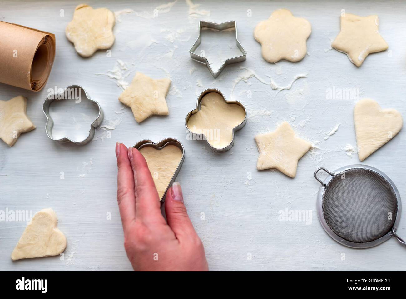 Top view of woman hands cooking a gingerbread cookie in the form of heart, star, cloud and flower. Christmas and New Year concept, festive Stock Photo