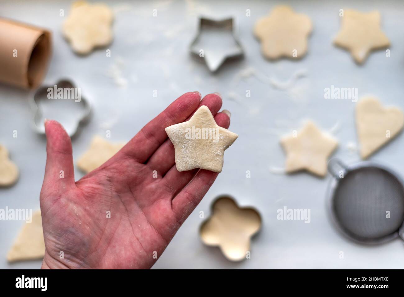 Top view of woman hands cooking a gingerbread cookie in the form of heart, star, cloud and flower. Christmas and New Year concept, festive Stock Photo