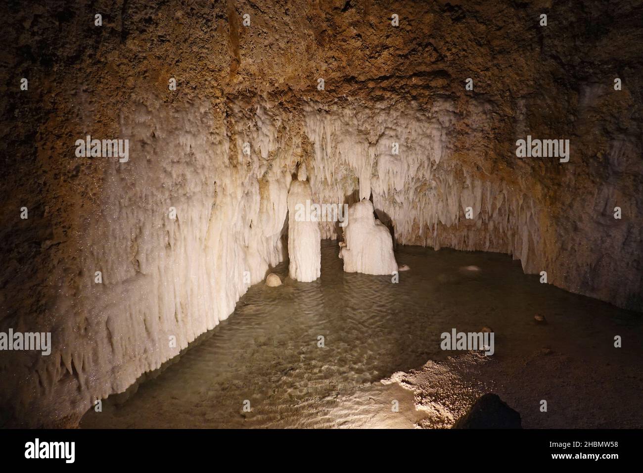 Interior of an underground cave with a small cascade and stalagnites and stalagtites. Stock Photo