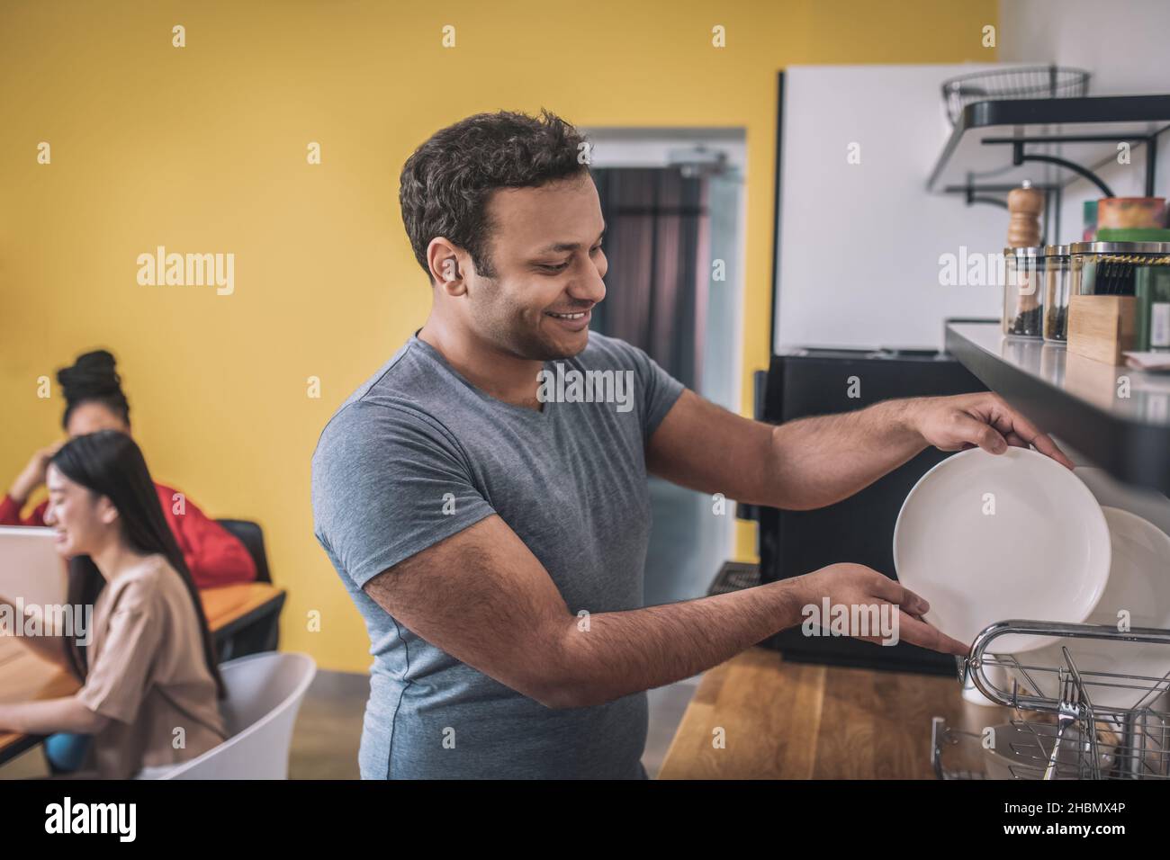 Guy stacking clean plates in office kitchen Stock Photo