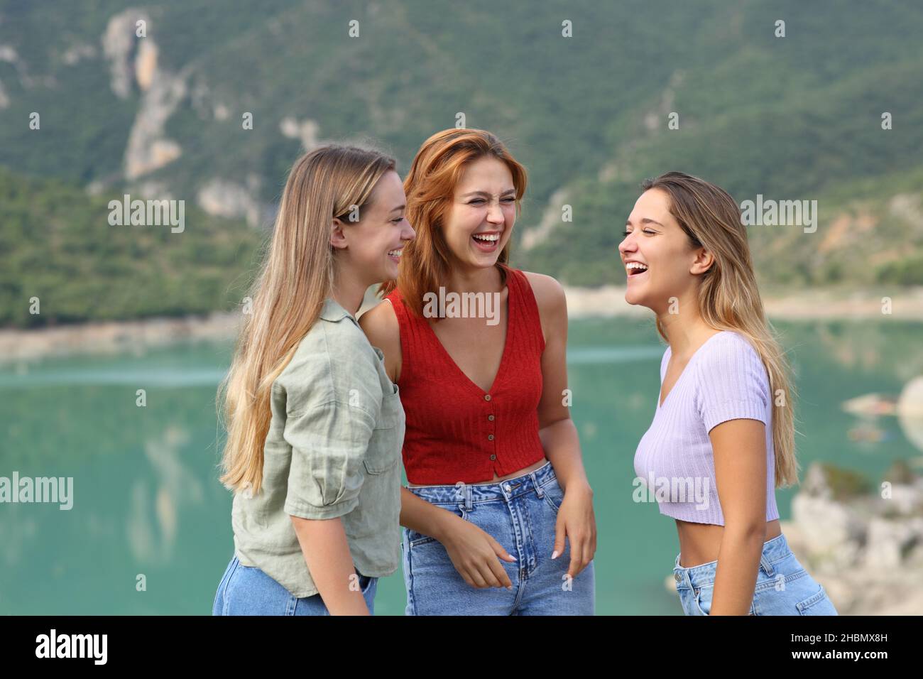 Three happy fiends laughing and talking in a lake on summer vacation Stock Photo