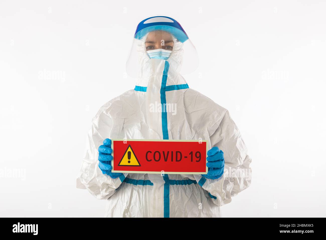 Médico enfermero con un equipo de protección personal y guantes de látex con un cartel rojo que dice: 'COVID-19'. Coronavirus, pandemia y concepto de Stock Photo