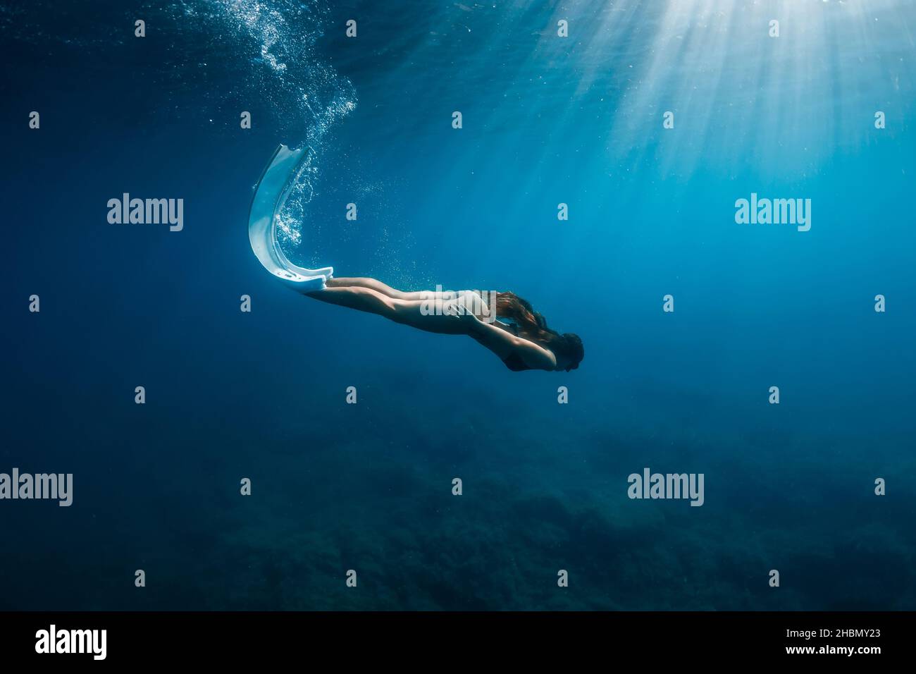 Freediver woman in bikini with fins dive underwater in deep blue ocean. Stock Photo