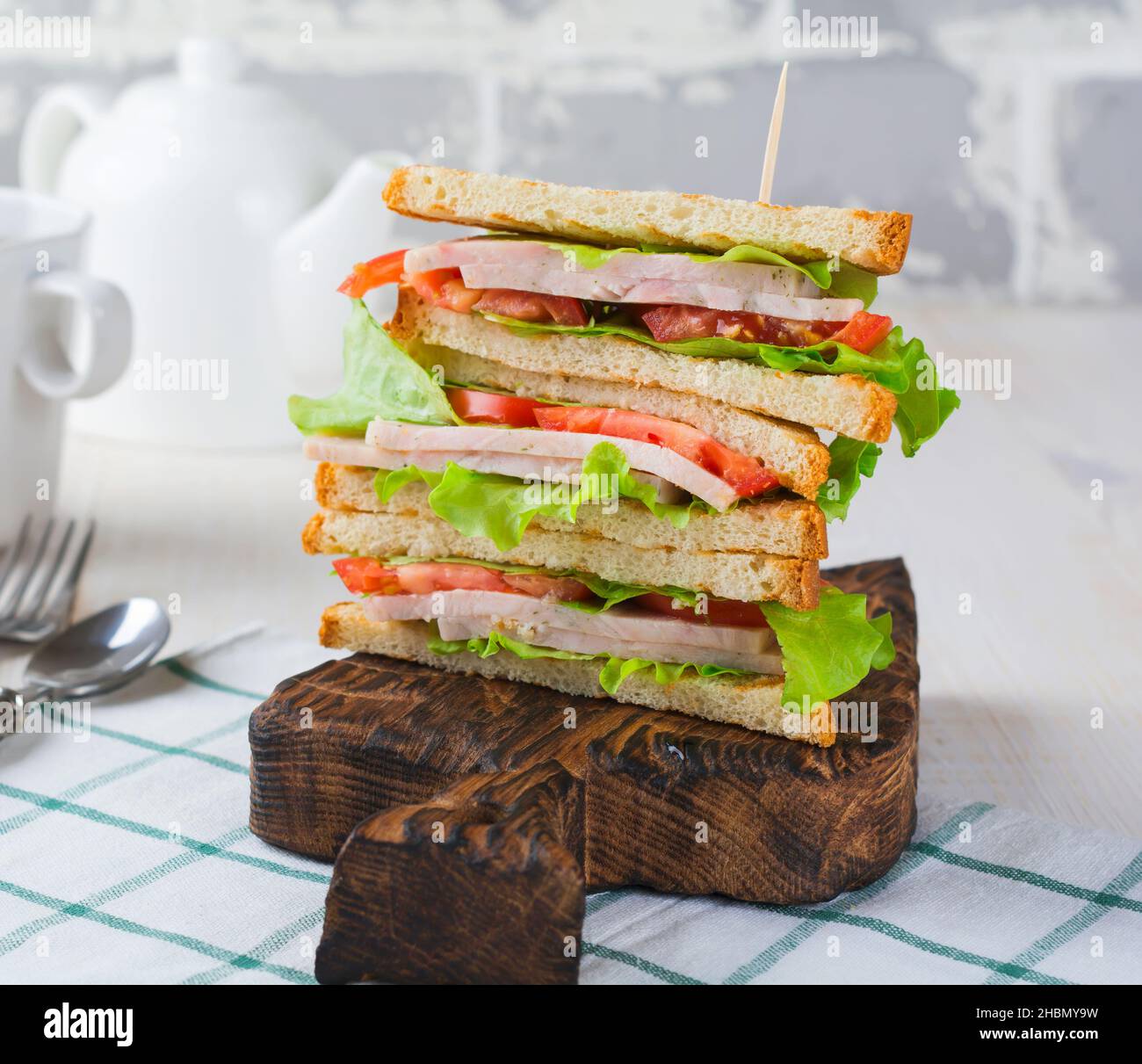 Sandwich for breakfast with stuffed tomatoes with ham and lettuce on a light wooden background. Selective focus. Stock Photo