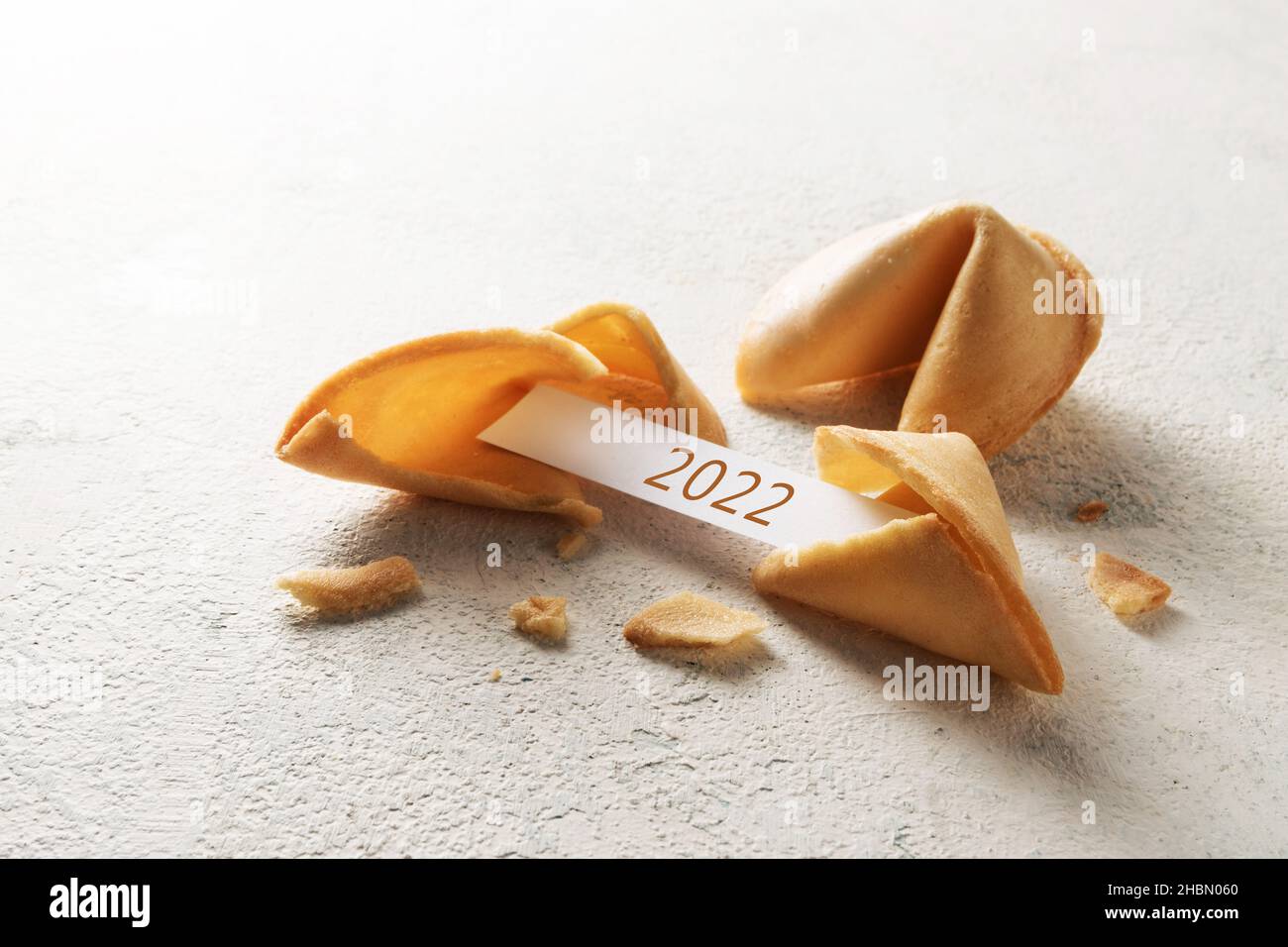 chinese fortune cookies, one is cracked with paper slip fshowing New Year 2022 on a light background with copy space, selected focus, narrow depth of Stock Photo