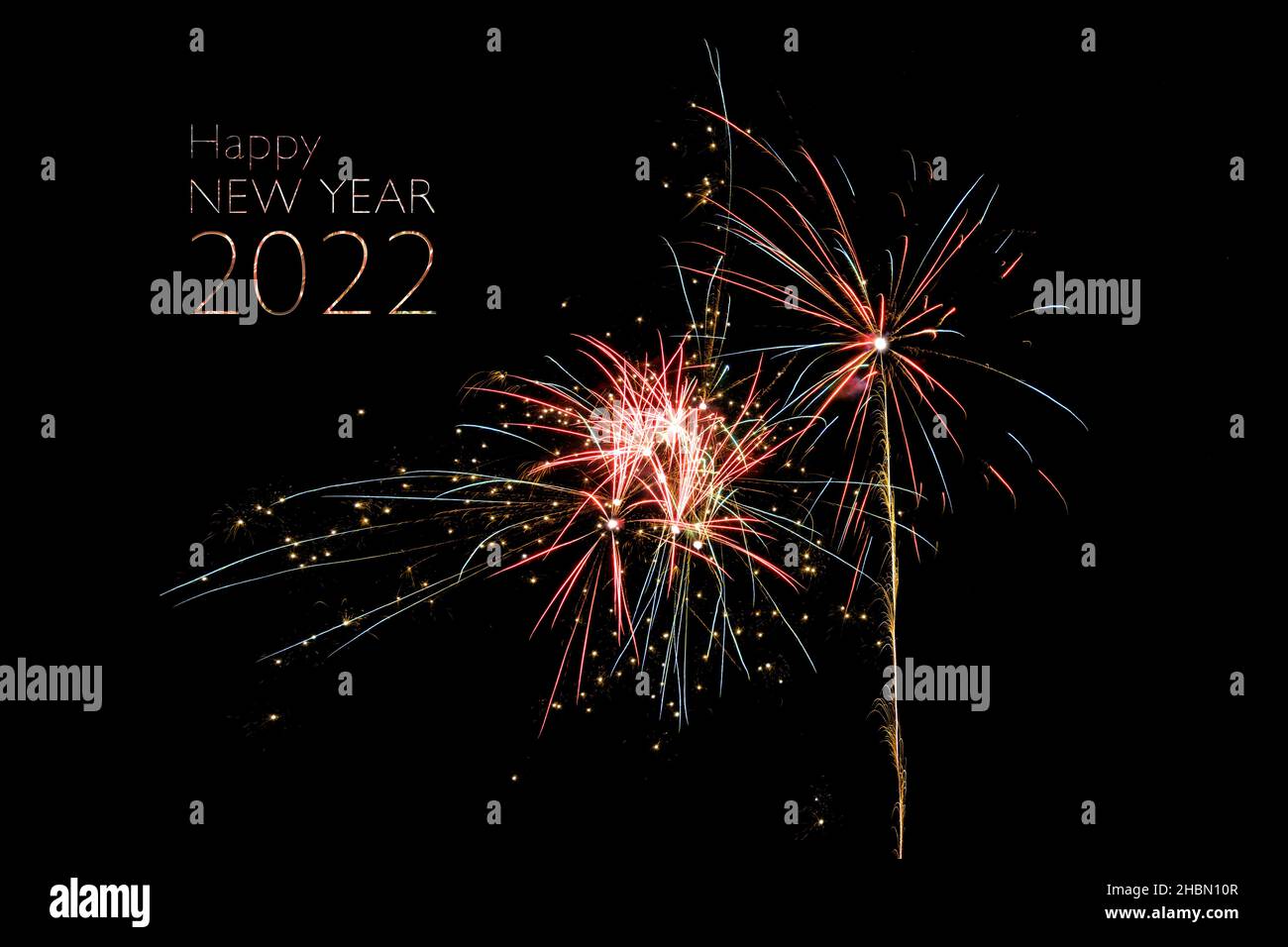 Happy New Year 2022 text and exploding colorful fireworks rockes against a black night sky, copy space Stock Photo
