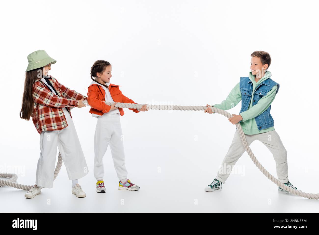 side view of cheerful girls pulling rope while playing tug of war game