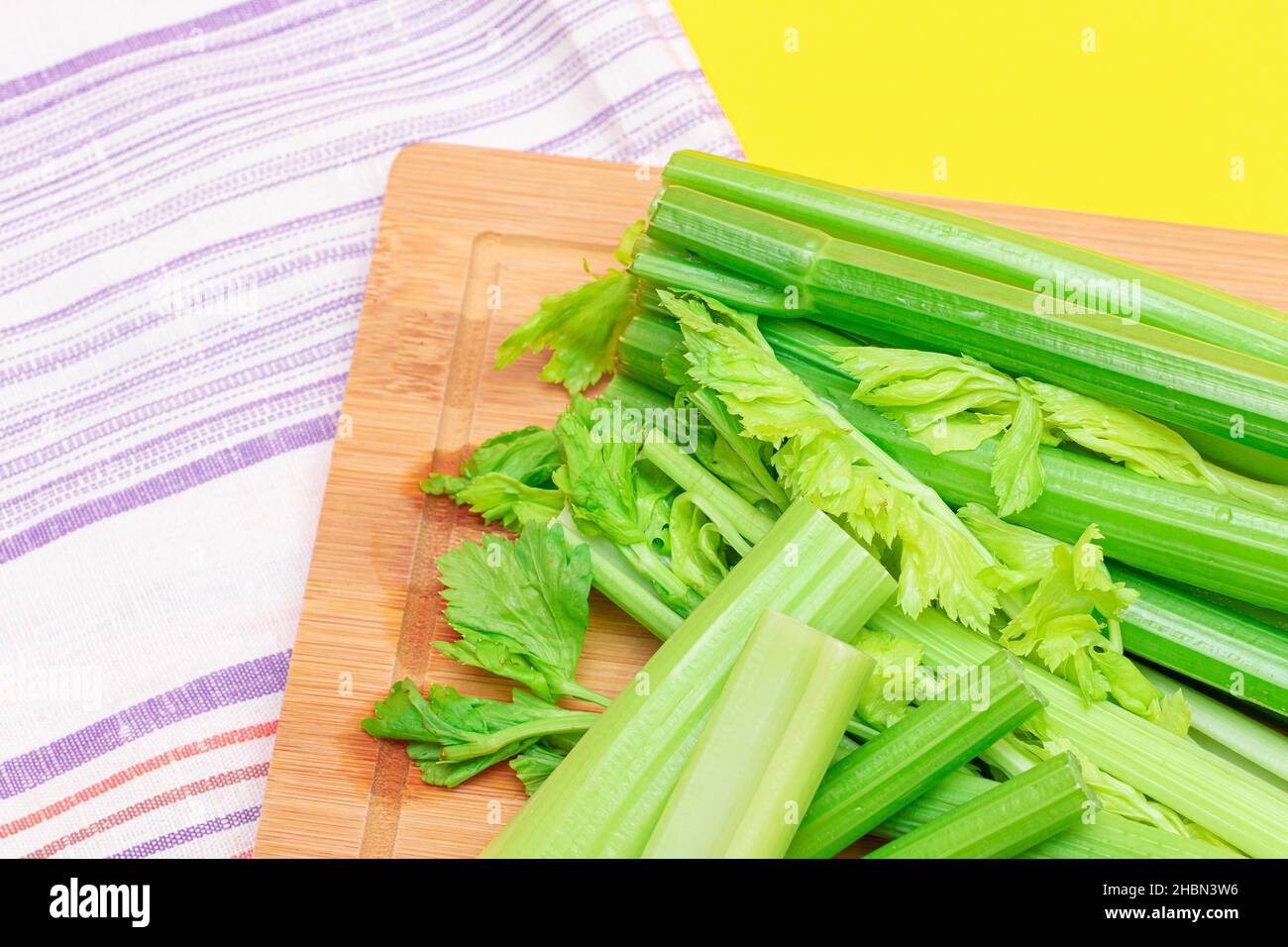 Fresh Celery Stem and Chopped Celery Sticks on Wooden Cutting Board