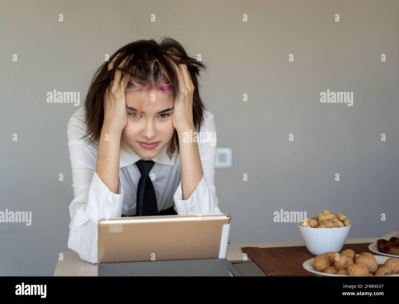 woman with her hands on her head frustrated in front of her tablet, staring at the camera Stock Photo