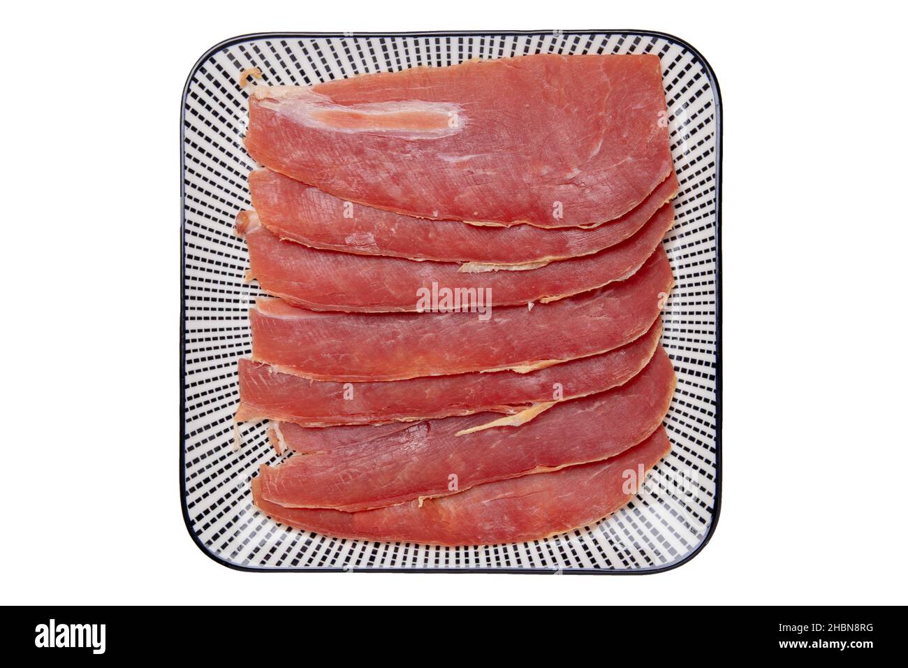Spanish food. Top view of pieces of sliced dry spanish ham (Jamon Serrano) or italian parma prosciutto crudo on a plate isolated on a white background Stock Photo