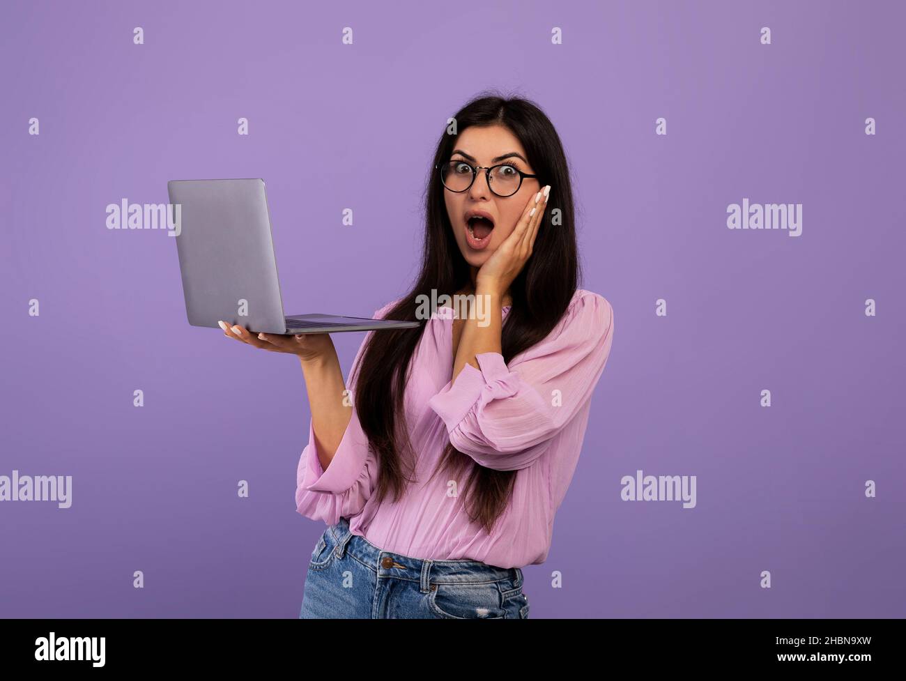 Shocked armenian woman holding laptop, having problems with computer, suffering bad internet connection Stock Photo