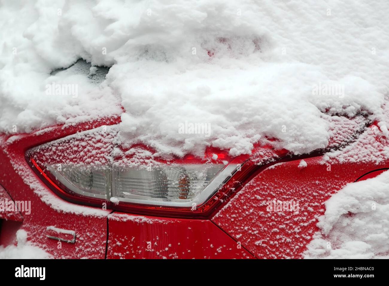 Hood red metal car with headlight in the snow close up, Light passenger car luxury class under snow cover. Stock Photo