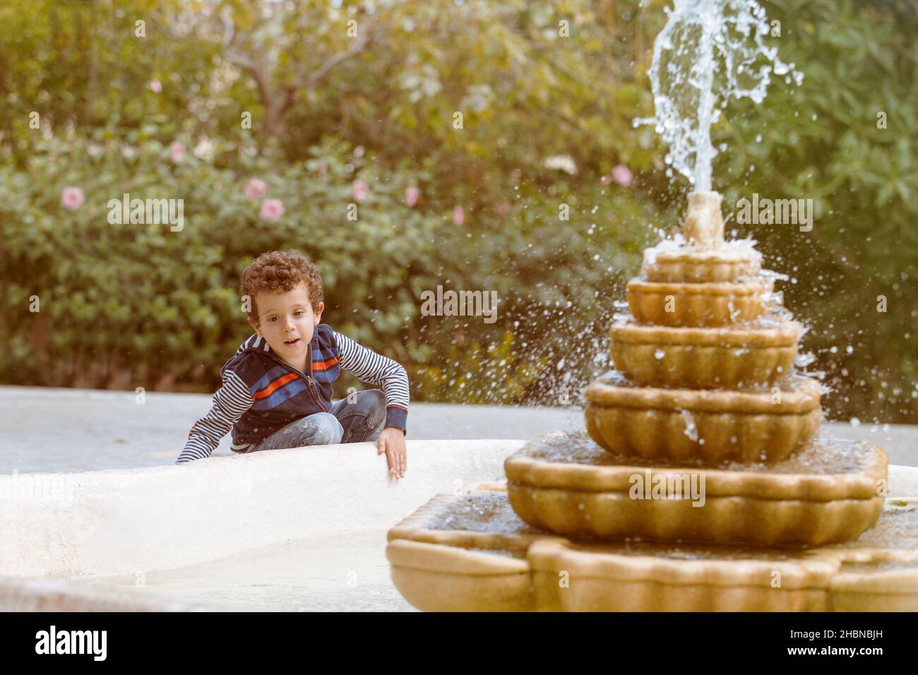 beautiful caucasian boy by a stone fountain at sunset Stock Photo