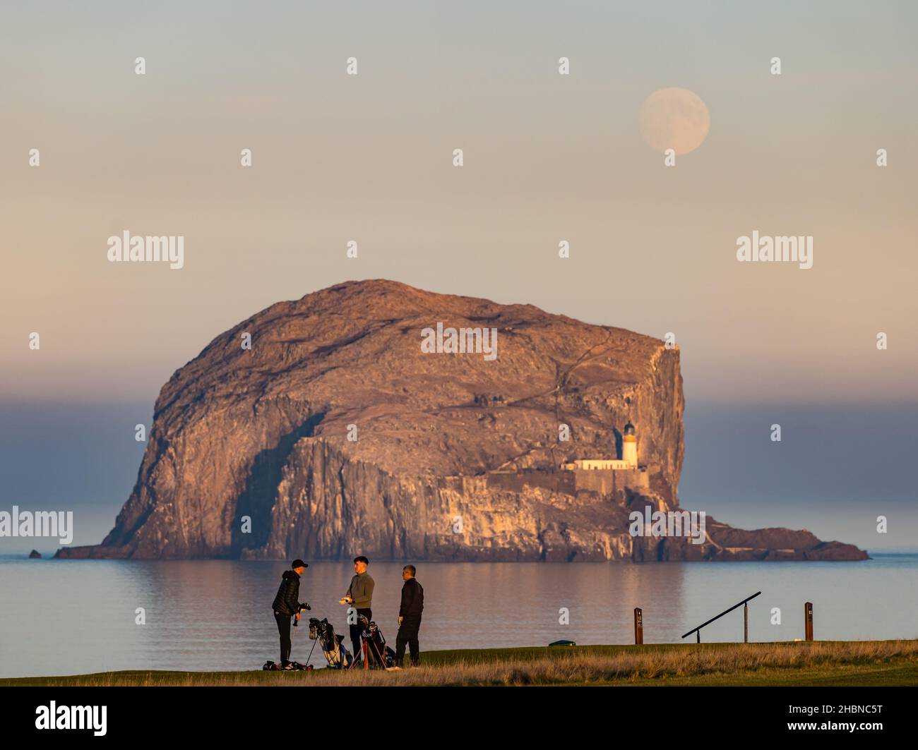 Men playing golf at dusk on Glen golf course, North Berwick in front of Bass Rock, Firth of Forth, Scotland, UK Stock Photo