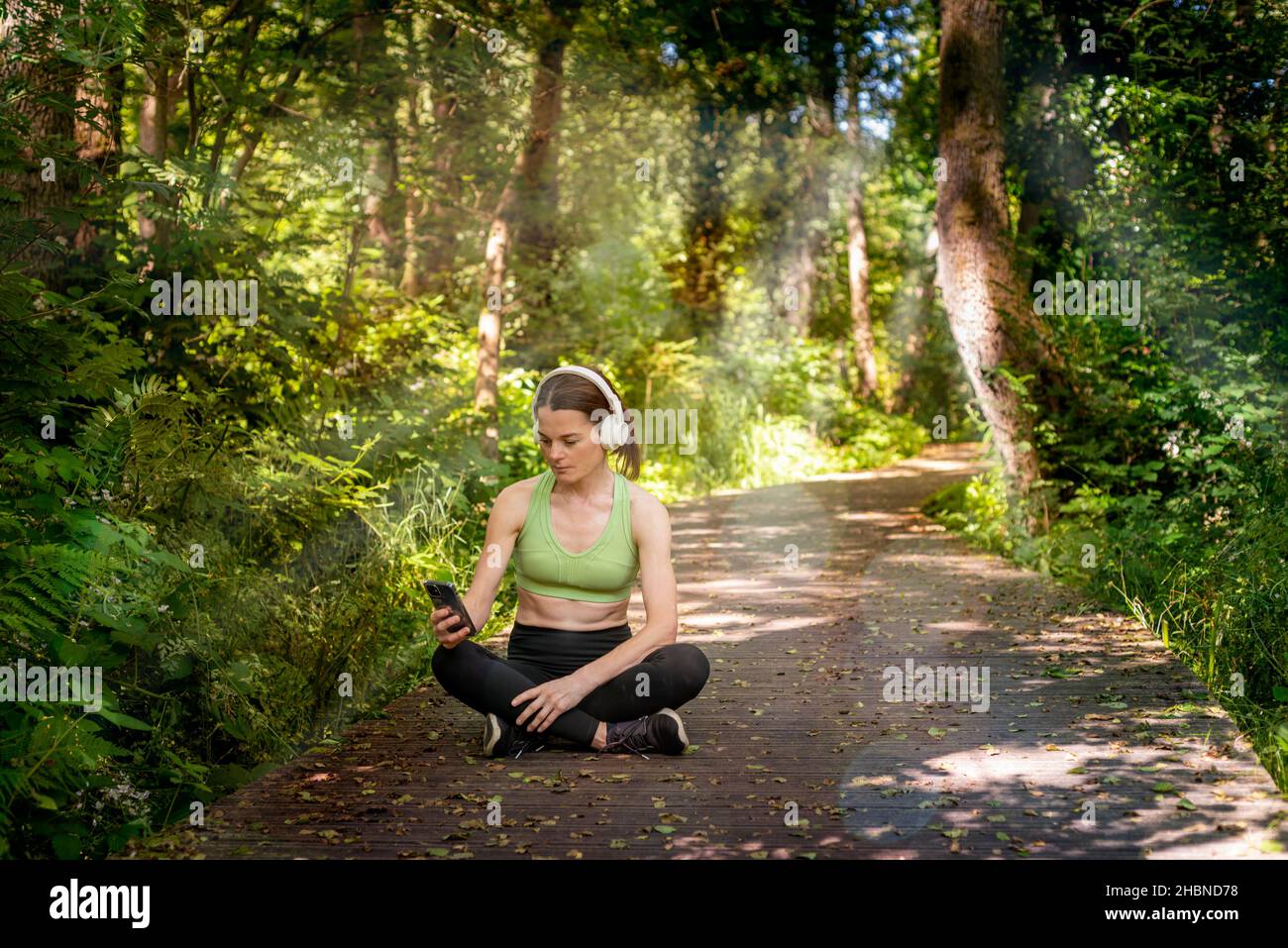 Woman resting while exercising, listening to music on headphones and selecting from a play list. Stock Photo