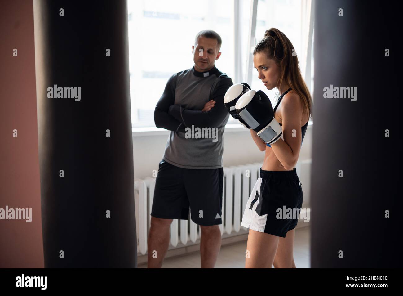 Woman training boxing with personal trainer. Instructor teaching female boxer fighting practice